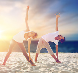 Image showing couple making yoga exercises on beach