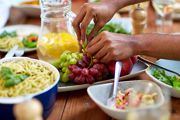 Image showing hands taking grape from plate with fruits