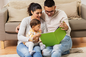 Image showing happy family with baby reading book at home