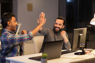 Image showing creative team making high five at night office