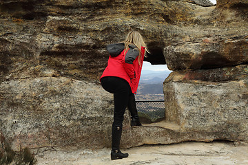 Image showing A woman looking through the cave opeing with views over a valley