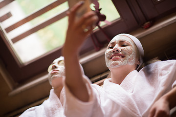 Image showing women is getting facial clay mask at spa