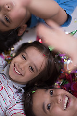 Image showing kids  blowing confetti while lying on the floor