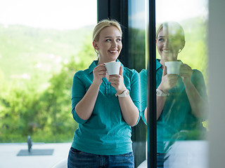 Image showing young woman drinking morning coffee by the window