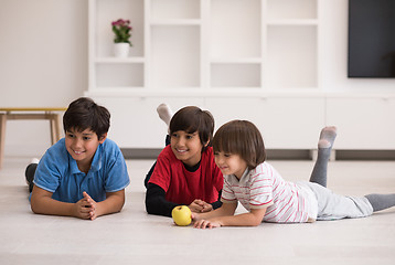 Image showing boys having fun with an apple on the floor