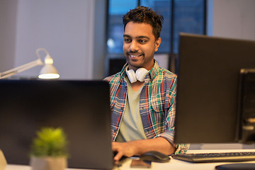 Image showing creative man with laptop working at night office