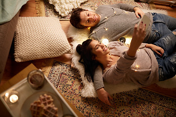 Image showing couple lying on floor and making selfie at home