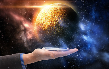 Image showing hand holding smartphone over planet in space