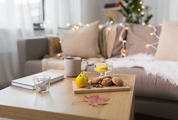 Image showing oat cookies, book, tea and lemon on table at home