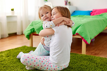 Image showing happy little girls or sisters hugging at home