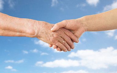 Image showing close up of senior and young woman hands over sky