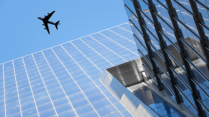 Image showing a plane flying over modern buildings of New York City