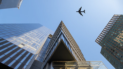 Image showing a plane flying over modern buildings of New York City