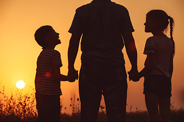 Image showing Father and children standing in the park at the sunset time. 