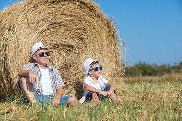 Image showing Father and son sitting in the park at the day time.