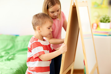 Image showing happy kids drawing on chalk board at home