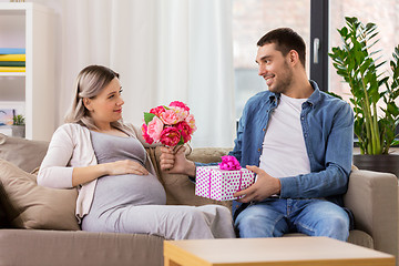 Image showing man giving flowers to pregnant woman at home