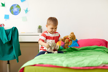 Image showing happy little boy playing with plush toys at home