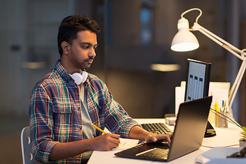 Image showing creative man with laptop working at night office