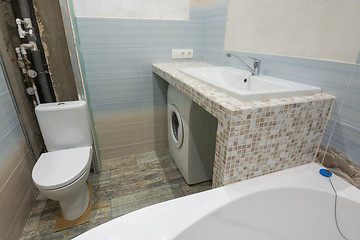 Image showing Unfinished repairs in the bathroom, a pedestal under the washbasin, under which there is a washing machine, and a toilet bowl