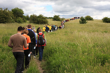 Image showing People walking in a line towards the tent on the top mof the hill.