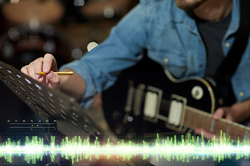 Image showing musician with guitar and music book at studio