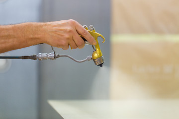 Image showing worker hand sprays urethane finish to board