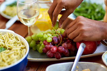 Image showing hands taking grape from plate with fruits
