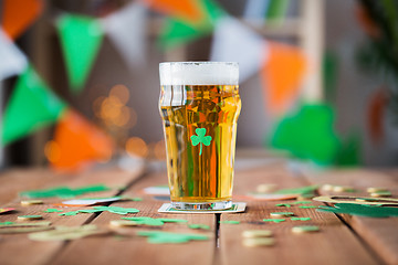 Image showing glass of beer, shamrock and coins on wooden table