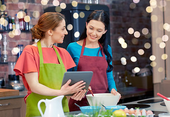 Image showing happy women with tablet pc cooking in kitchen