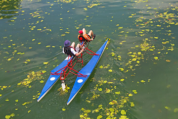 Image showing Man and woman ride with floating pedal bicycle boats across the 