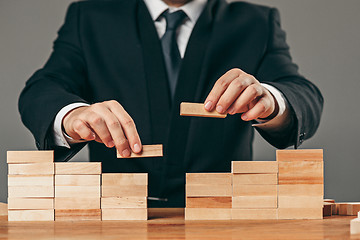 Image showing Man and wooden cubes on table. Management concept