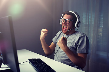 Image showing man in headset playing computer video game at home