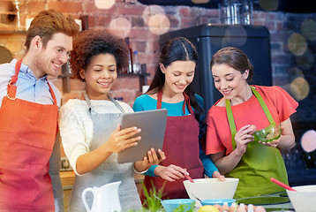 Image showing happy friends with tablet pc cooking in kitchen