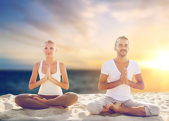 Image showing couple making yoga and meditating on beach