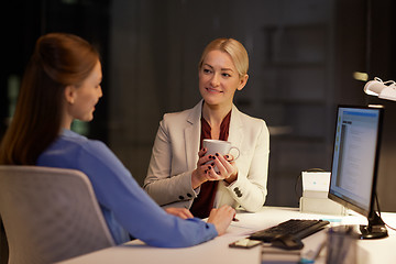 Image showing businesswomen drinking coffee at night office