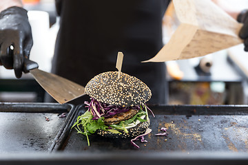 Image showing Chef preparing burgers at grill plate on international urban street food festival.