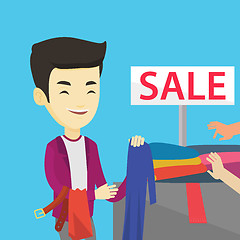 Image showing Young man choosing clothes in shop on sale.