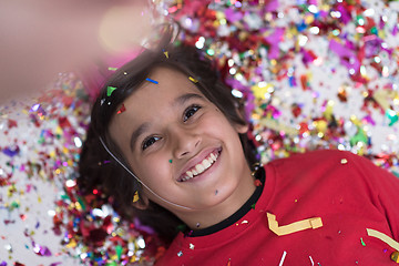 Image showing kid blowing confetti while lying on the floor