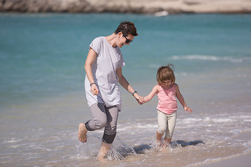 Image showing mother and daughter running on the beach