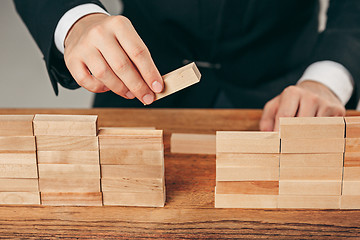 Image showing Man and wooden cubes on table. Management concept