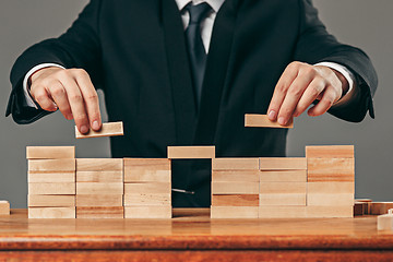 Image showing Man and wooden cubes on table. Management concept