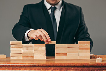 Image showing Man and wooden cubes on table. Management concept