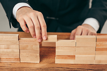 Image showing Man and wooden cubes on table. Management concept