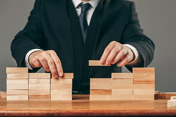 Image showing Man and wooden cubes on table. Management concept