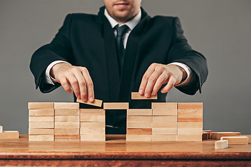 Image showing Man and wooden cubes on table. Management concept