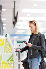 Image showing Casual caucasian woman using smart phone application and check-in machine at the airport getting the boarding pass.