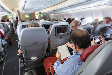 Image showing Interior of large commercial airplane with passengers on their seats during flight.