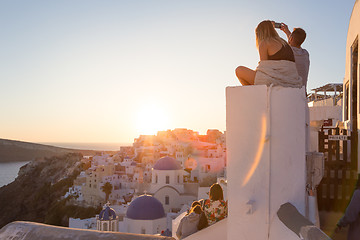 Image showing Couple watching sunrise and taking vacation photos at Santorini island, Greece.