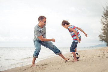 Image showing Father and son playing football on the beach at the day time.